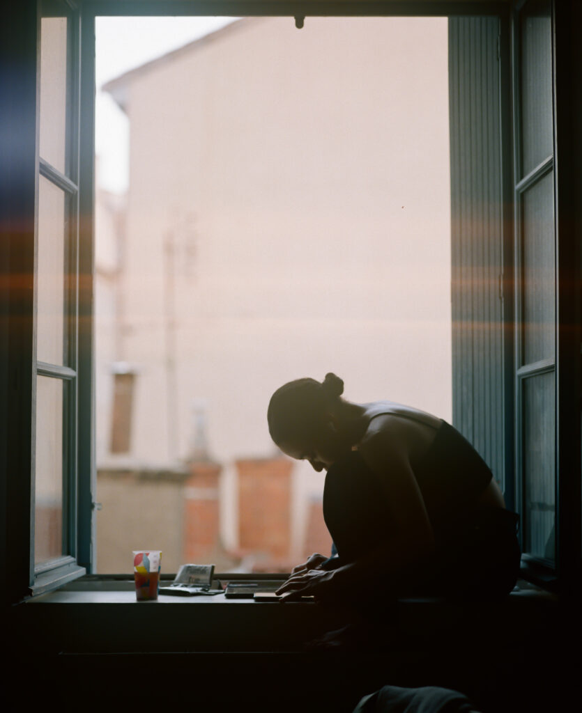 Une personne est assise sur le rebord d'une fenêtre.
