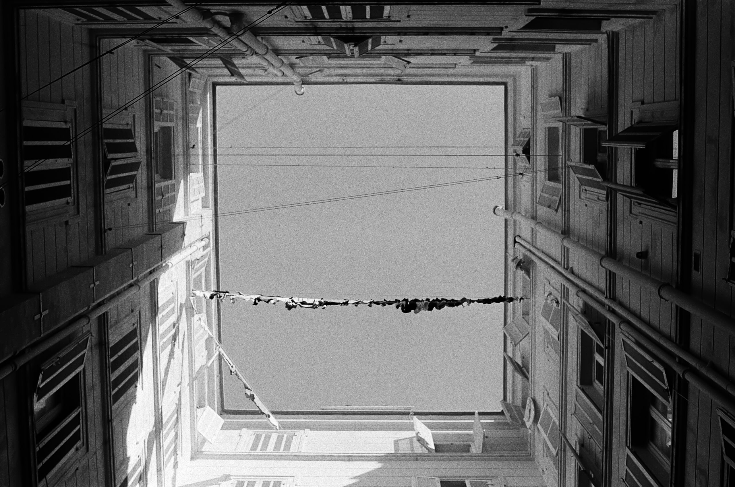 photo en noir en blanc avec vu sur le ciel dans une cours d'immeuble en forme de carré